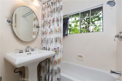 Remodeled bathroom with a pedestal sink & sparkling tub.