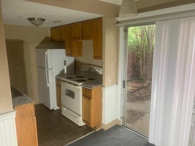 Kitchen with white appliances, wainscoting, brown cabinetry, and light countertops