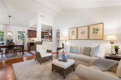 Living area with wood finished floors, beamed ceiling, a chandelier, and high vaulted ceiling