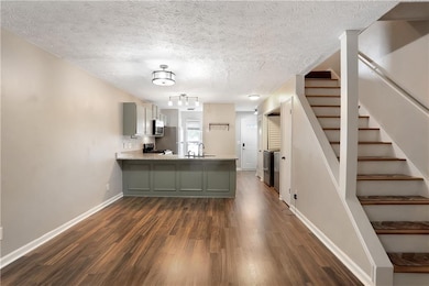 Kitchen with a peninsula, dark wood-style flooring, stainless steel microwave, gray cabinets, and electric range