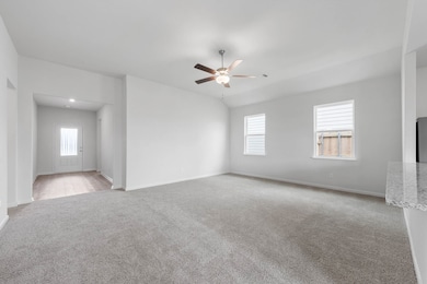 Spare room featuring light carpet, plenty of natural light, ceiling fan, and lofted ceiling