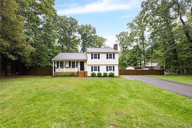Split level home with a chimney, a porch, and asph