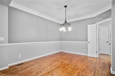 Empty room with crown molding, a chandelier, wood finished floors, and baseboards