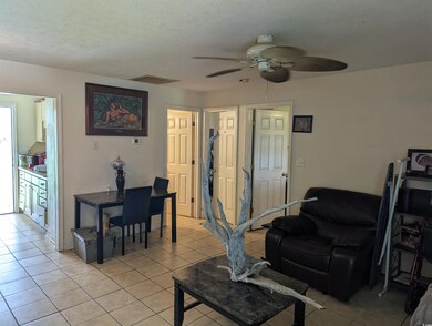 Living room featuring a ceiling fan, light tile patterned flooring, and a textured ceiling