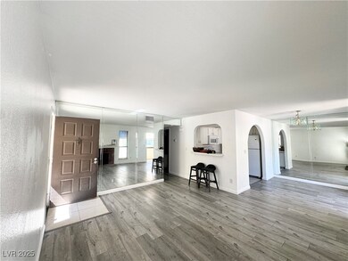 Living room with arched walkways and wood finished floors