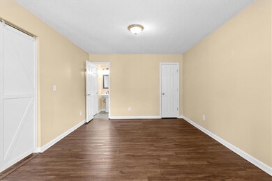 Unfurnished bedroom with dark wood-style floors, a textured ceiling, and connected bathroom