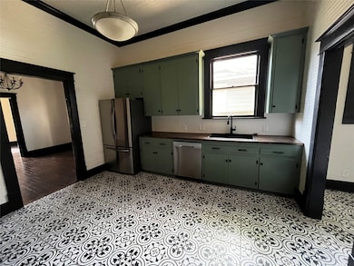 Kitchen featuring green cabinets, stainless steel appliances, and dark countertops