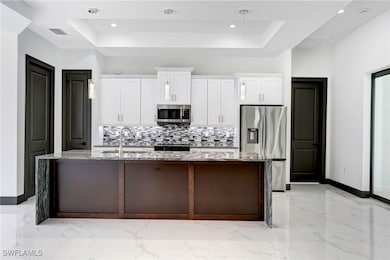 Kitchen featuring an island with sink, a raised ce