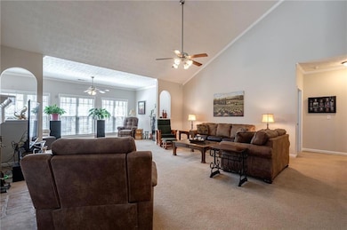 Living room with light colored carpet, ceiling fan, ornamental molding, and baseboards