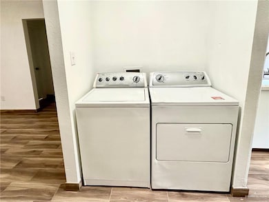 Laundry room with washer and dryer, light wood-type flooring, and a textured wall