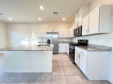 Kitchen featuring stainless steel appliances, light stone counters, white cabinetry, an island with sink, and recessed lighting