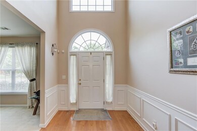Entrance foyer featuring light wood finished floors, a wainscoted wall, plenty of natural light, a decorative wall, and a high ceiling