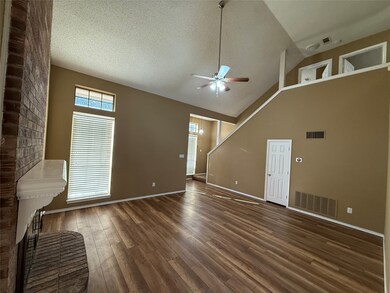 Unfurnished living room with a brick fireplace, dark wood-style floors, ceiling fan, a textured ceiling, and high vaulted ceiling