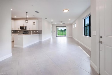 Kitchen featuring electric range oven, stainless steel microwave, open floor plan, backsplash, and a peninsula