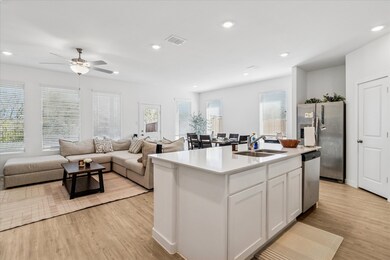 Kitchen with white cabinets, open floor plan, stainless steel appliances, light wood finished floors, and recessed lighting