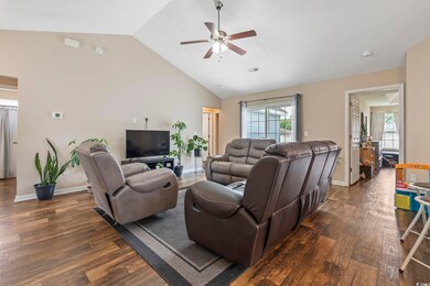 Living area featuring dark wood finished floors, a ceiling fan, vaulted ceiling, and baseboards