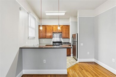 Kitchen featuring freestanding refrigerator, stove, light wood finished floors, decorative light fixtures, and a peninsula