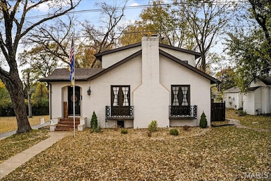View of front facade featuring a chimney, brick siding, and french doors