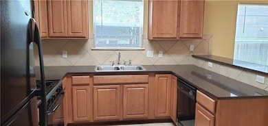 Kitchen featuring black appliances, a sink, backs