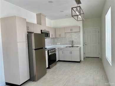 Kitchen featuring appliances with stainless steel finishes, light countertops, decorative backsplash, and plenty of natural light