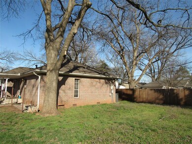 View of side of home with fence, crawl space, bric