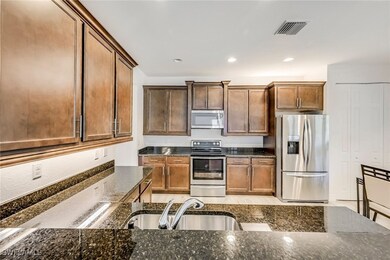 Kitchen with appliances with stainless steel finishes, recessed lighting, dark stone countertops, and brown cabinets