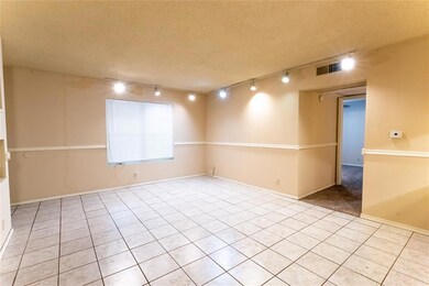 Unfurnished room with track lighting, light tile patterned flooring, and a textured ceiling