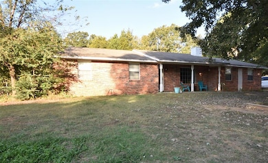 Front view of property with brick siding, a yard, a chimney, and a patio area