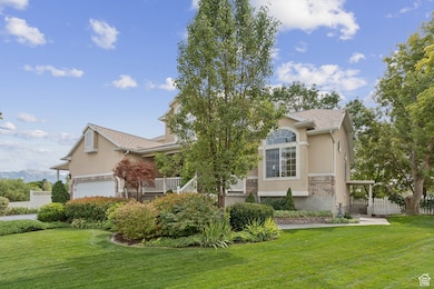 View of property hidden behind natural elements featuring stucco siding, a shingled roof, and a garage