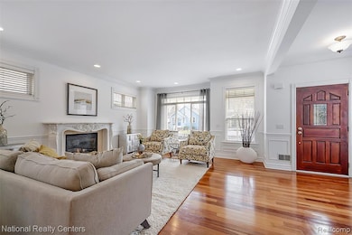 Living area featuring ornamental molding, a premium fireplace, light wood-style flooring, a decorative wall, and a wainscoted wall