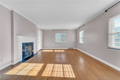 Unfurnished living room with a premium fireplace, light wood-type flooring, and ornamental molding
