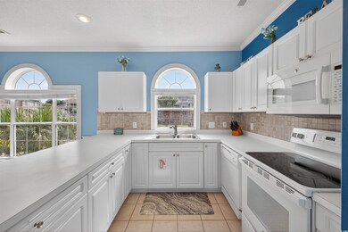 Kitchen featuring white appliances, ornamental molding, light countertops, a textured ceiling, and white cabinetry