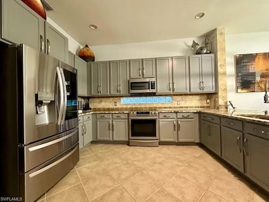 Kitchen featuring appliances with stainless steel finishes, gray cabinets, tasteful backsplash, light stone counters, and recessed lighting