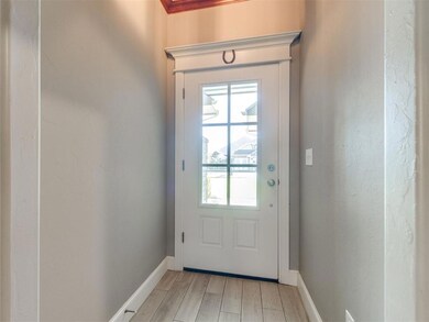 Doorway with wood finished floors and a textured wall