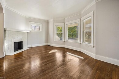 Unfurnished living room featuring dark hardwood floors, a brick fireplace, and ornamental molding