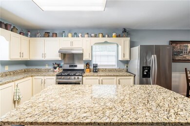 Kitchen featuring stainless steel appliances, a center island, light stone countertops, and under cabinet range hood