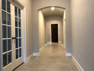 Hallway with light tile patterned floors and arched walkways