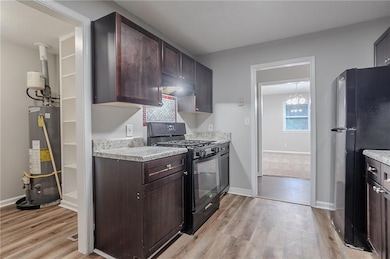 Kitchen featuring black appliances, water heater, light wood-style flooring, and light countertops