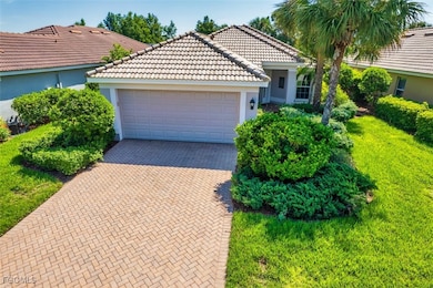 Ranch-style house with stucco siding, decorative driveway, a tiled roof, a front yard, and an attached garage