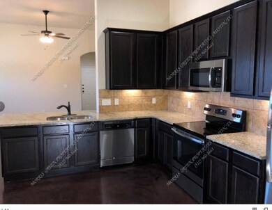 Kitchen with appliances with stainless steel finishes, tasteful backsplash, concrete floors, a peninsula, and light stone counters