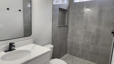 Full bathroom with toilet, vanity, and tiled shower