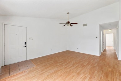Empty room featuring light wood-type flooring, ceiling fan, and vaulted ceiling