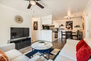Living room with light wood finished floors, crown