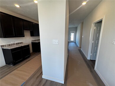 Kitchen with dark wood-style floors, dark cabinetry, recessed lighting, and light stone counters