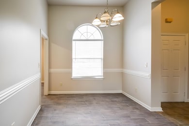 Empty room with a chandelier and baseboards
