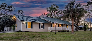 View of front of house featuring covered porch, a chimney, a standing seam roof, and metal roof