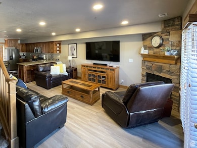 Living area with a fireplace, light wood finished floors, stairs, recessed lighting, and a textured ceiling