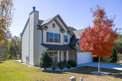 Traditional home featuring covered porch, concrete driveway, a front yard, and brick siding