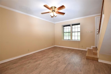 Empty room with a ceiling fan, ornamental molding, light wood finished floors, and baseboards