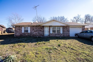 Ranch-style house featuring brick siding, an attached garage, and a front yard